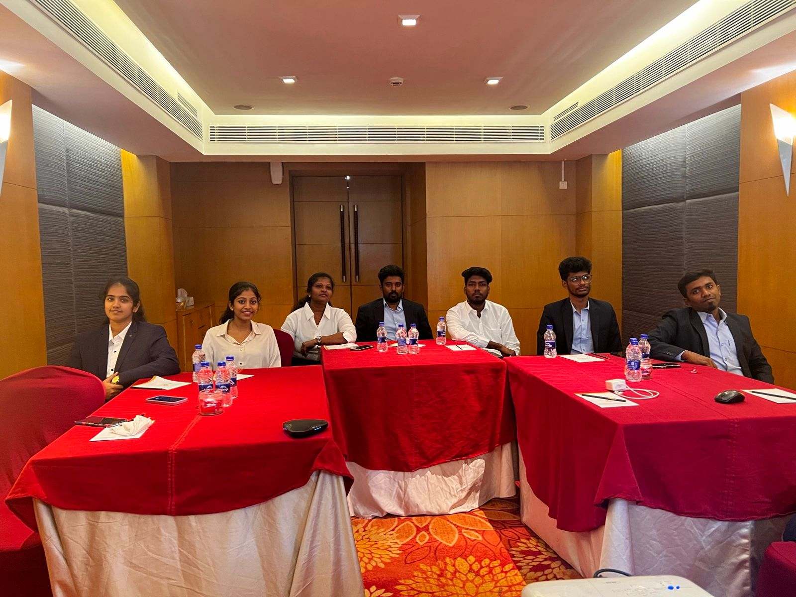 Seven members of Missan's India team seated at red-covered tables in a hotel meeting room