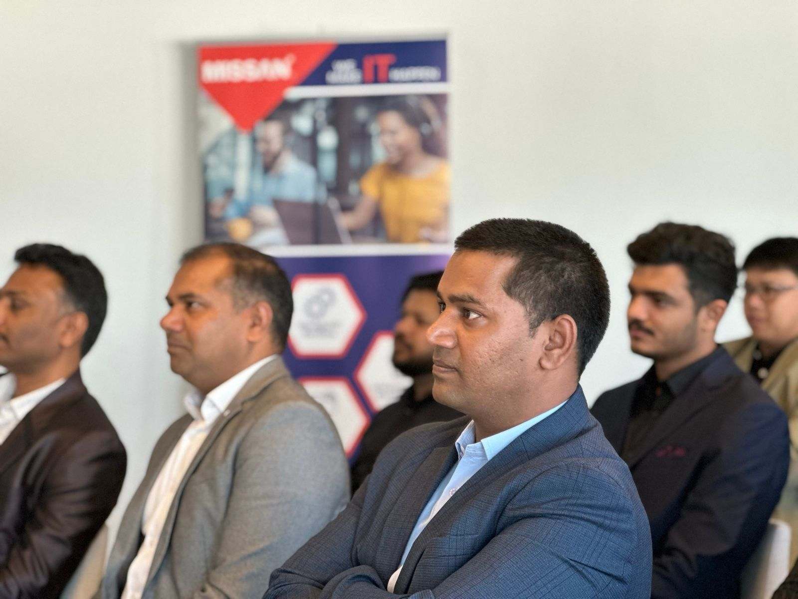 A row of Missan staff in suits listening to a presentation