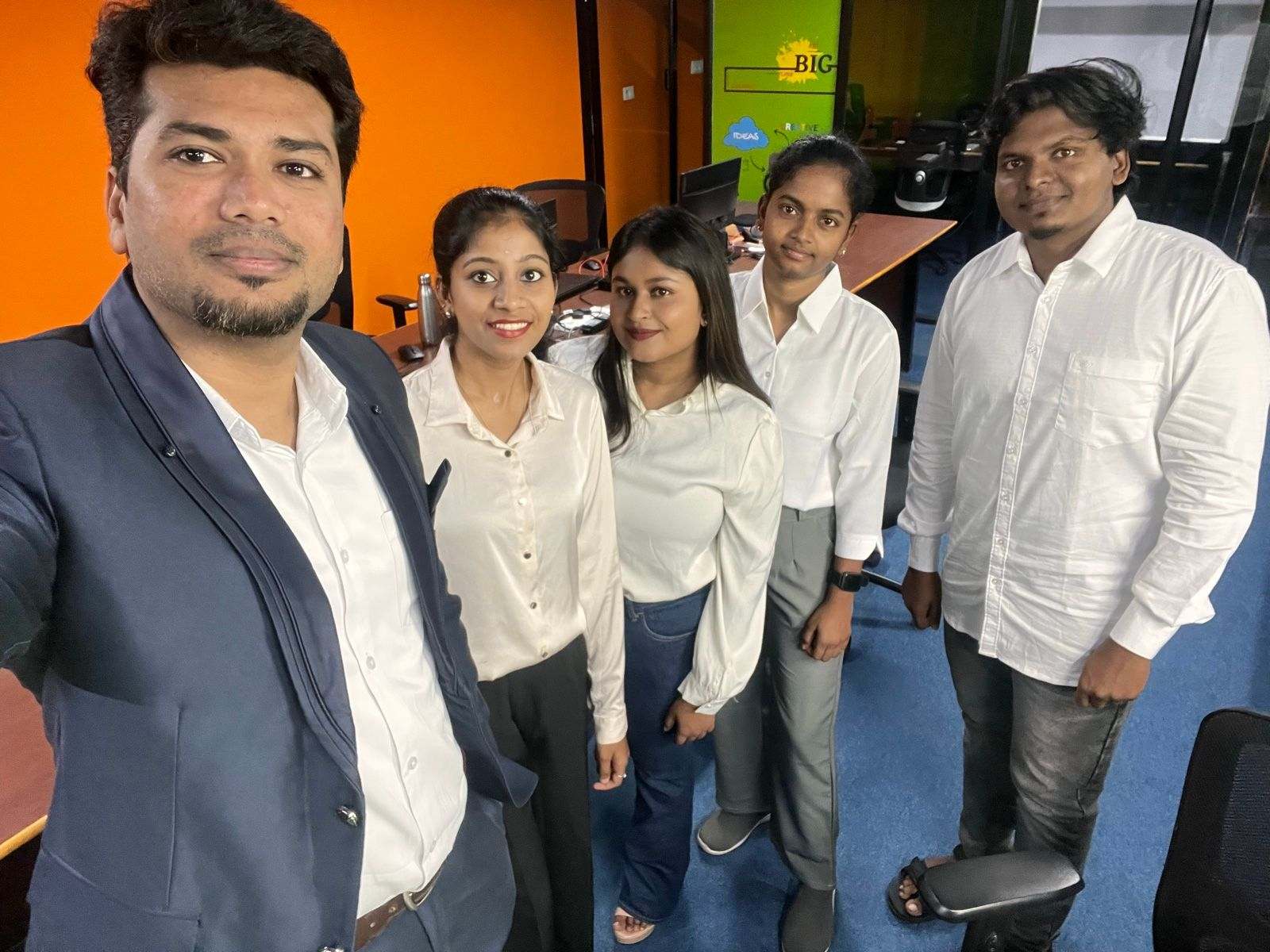 Five members of Missan's India team in white shirts taking a selfie in their workspace