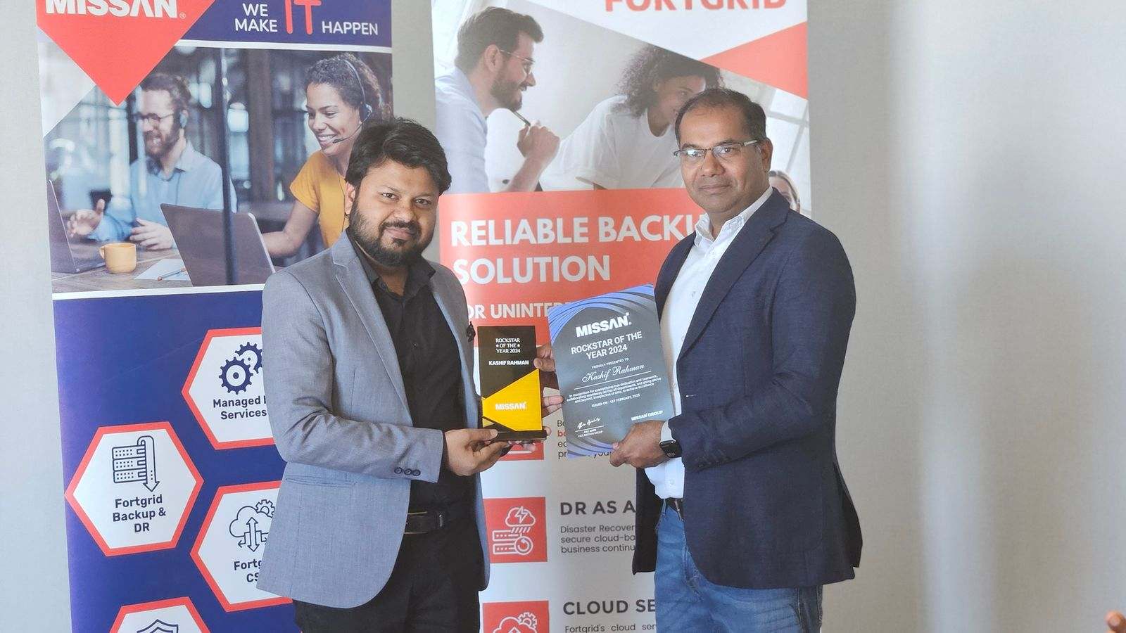A certificate and trophy being handed over between two Missan team members in front of Missan service banners