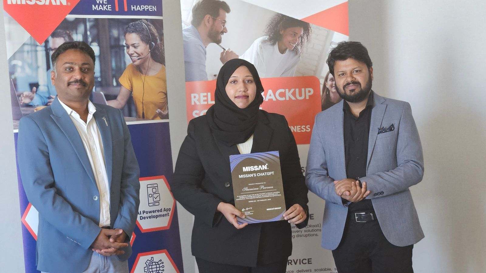 A Missan team member holding a certificate between two colleagues in front of Missan banners