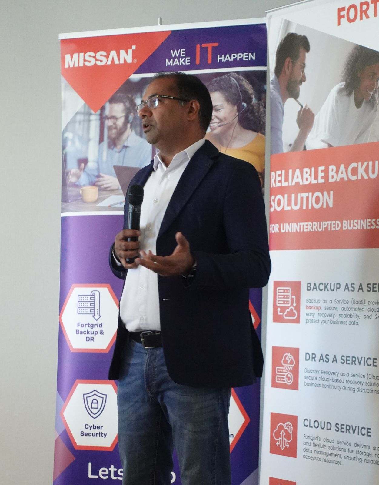 A Missan team member presenting beside banners for backup and disaster recovery and cyber security services