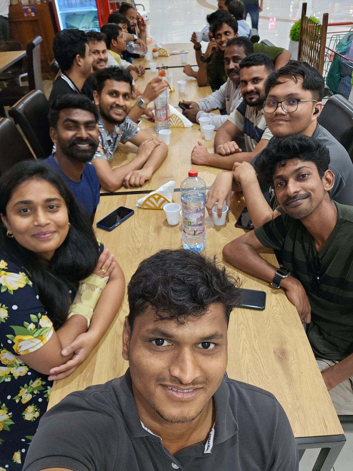 About fourteen Missan staff smiling round a food-court table in a group selfie