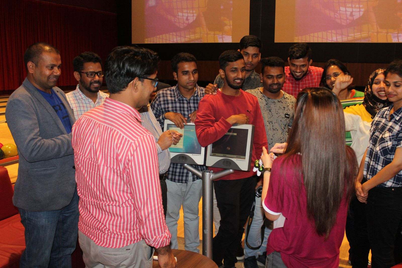 Missan team members in matching striped team tops gathered round a bowling scoring console