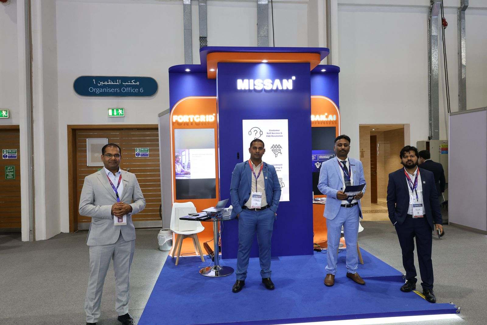 The whole Missan stand, with four team members in suits in front of the FortGrid, Missan and Missan.AI panels