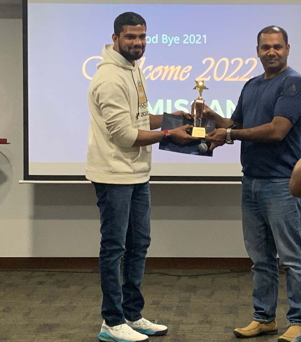 Two Missan staff smiling as a star trophy is handed over in front of a Welcome 2022 slide